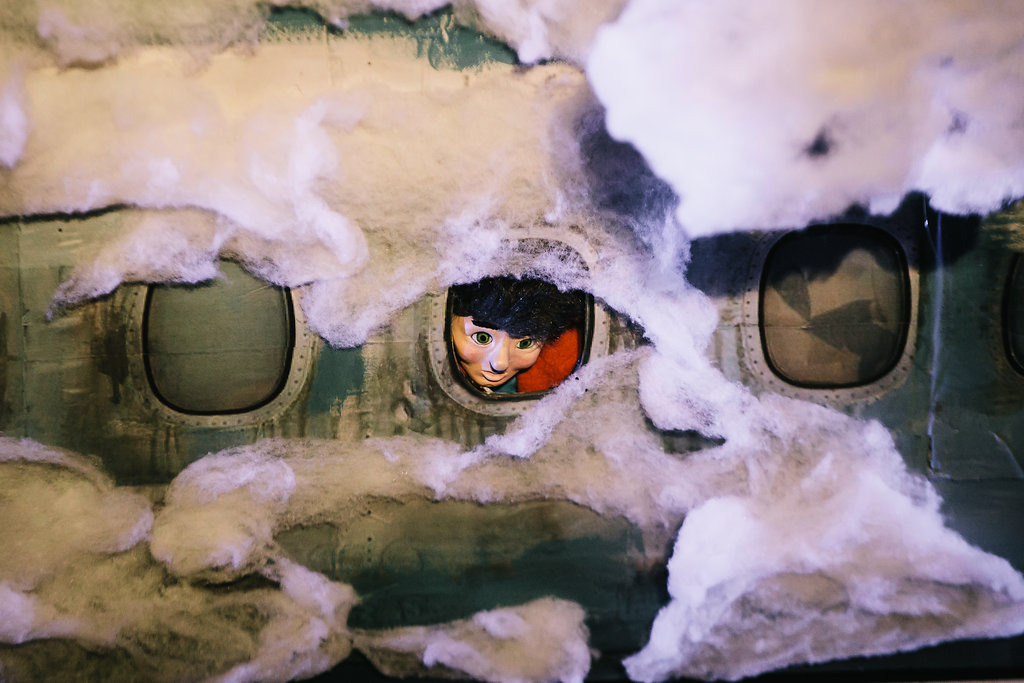 Puppet Peter looks out of an airplane window.